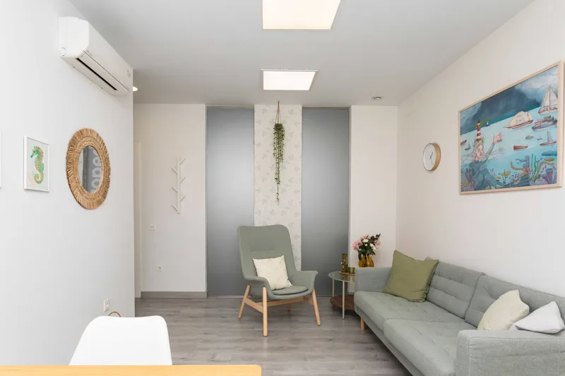 Zona común del centro, con sillón, espejo y láminas marinas