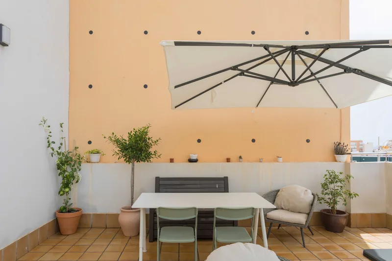 Zona de la terraza, con mesa y sombrilla